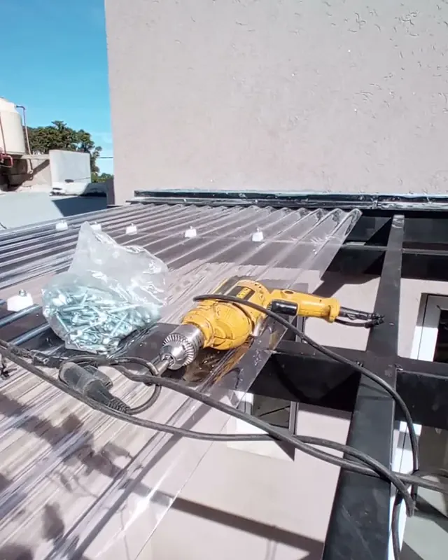 Instalación de planchas de policarbonato sobre una estructura metálica con taladro